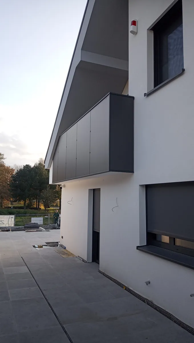 Balkon mit geschlossener Brüstung in Anthrazit an einem weißen Neubau