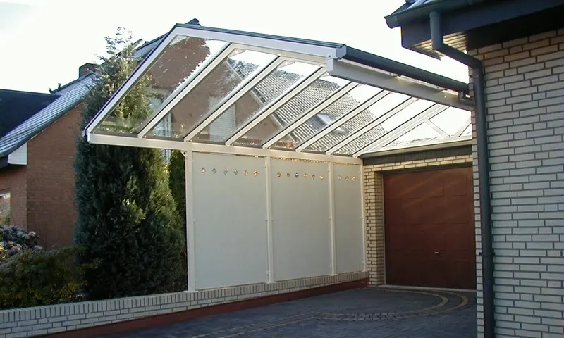 Carport mit Glasdach und Seitenwand vor einer Garage