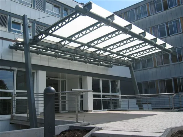 Großes Glasdach mit Fachwerkträgern vor einem Bürogebäude